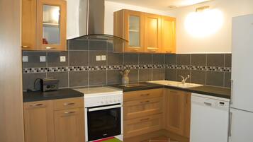 A modern kitchen with wooden cabinets, a built-in oven, a dishwasher, and a tiled backsplash.