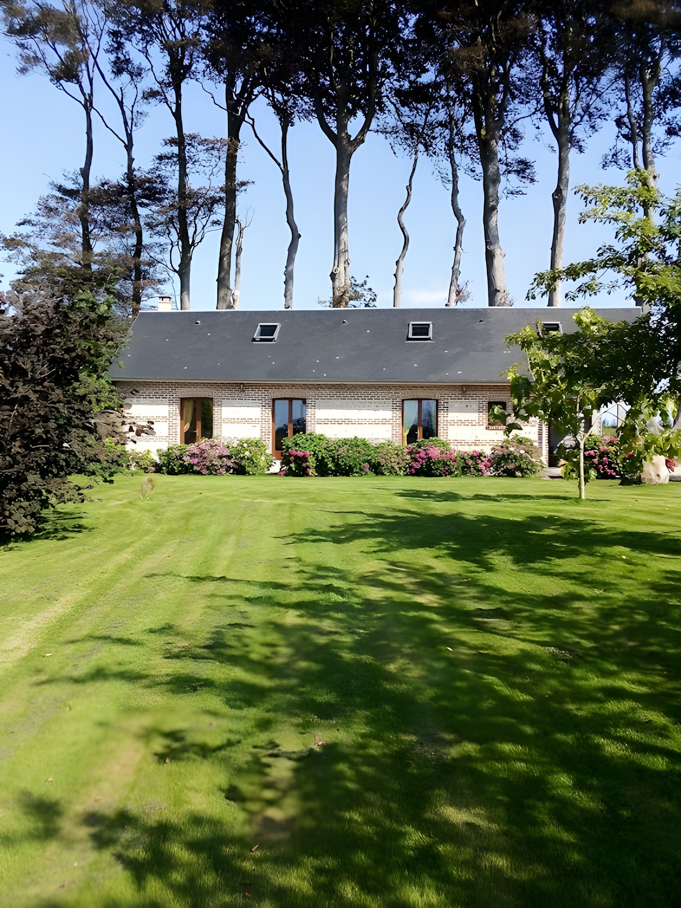 Une maison à deux étages avec une façade en briques, un toit en pente et une pelouse bien entretenue.