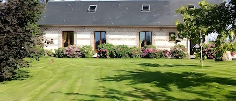 A two-story house with a brick facade, a sloped roof, and a well-maintained lawn.