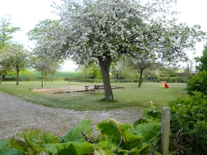 A park with a bench, a tree with white blossoms, and a red play structure.