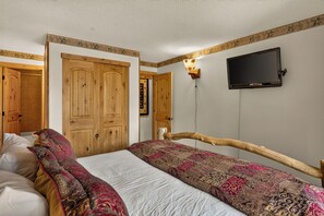 A bedroom with a bed, wooden wardrobe, and a television mounted on the wall. - Walk to Lifts, Main St! (Breckenridge)