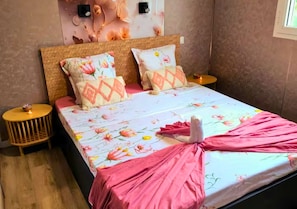 A bed with floral bedding, two pillows, a wooden headboard, and a bedside table with a lamp. - New Listing (Saint-André)