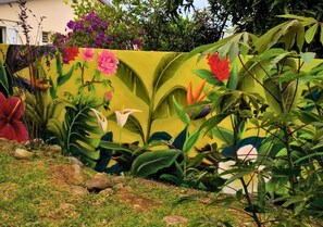 Ein Garten mit einer Wand, die mit einem floralen Wandbild bemalt ist.