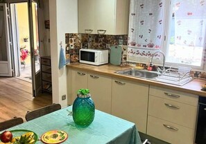 A kitchen with a microwave, sink, and a table with a green vase. - New Listing (Saint-André)