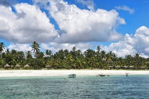 A beach with palm trees and thatched-roof huts. - Flat "Zanzi Dream" at The Soul with Pool, balcony, AC (Paje)