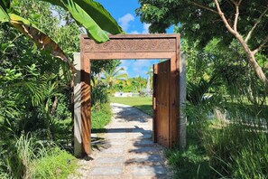 A wooden archway leading to a pathway surrounded by lush greenery. - Flat "Zanzi Dream" at The Soul with Pool, balcony, AC (Paje)