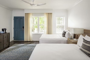 Una habitación de hotel con cama, mesita de noche, lámpara y ventana con cortinas.