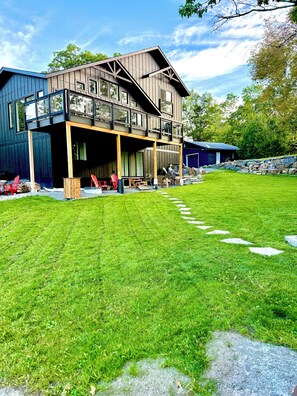 A two-story building with a covered outdoor area, a stone pathway, and a grassy lawn. - Brand New LakeHouse StrattCottage (Douro-Dummer)