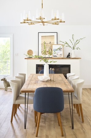 A dining room with a wooden table, six chairs, a chandelier, a fireplace, and framed artwork. - Brand New LakeHouse StrattCottage (Douro-Dummer)