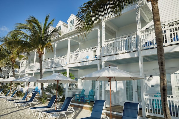 A beachfront hotel with multiple balconies, sun loungers, and umbrellas. - Quiet Key West Base | Garden View, Poolside Bar & 1.9 Mi To Smathers Beach (Key West)