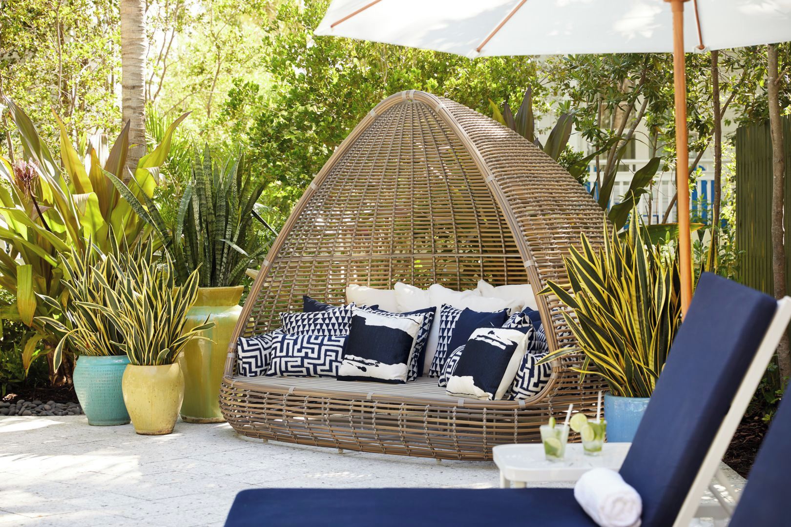 Unwind in a shaded daybed nook surrounded by tropical greenery.