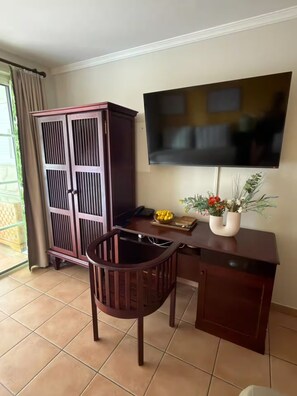 A room with a desk, chair, television, cabinet, and a window with curtains. - New Listing (Sainte-Luce)