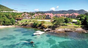A coastal resort with multiple buildings, a clear blue sea, and a boat on the water. - New Listing (Sainte-Luce)