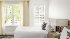 Ein Hotelzimmer mit einem großen Bett, einem Nachttisch mit Lampe und einem Fenster mit Jalousien.