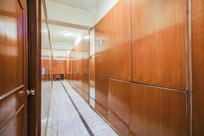 Un pasillo con paneles de madera y suelo de baldosas, que conduce a una habitación con una puerta.