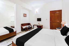Ein Hotelzimmer mit zwei Betten, einem Schreibtisch, einem Stuhl, einem Fernseher und einer Holztür.