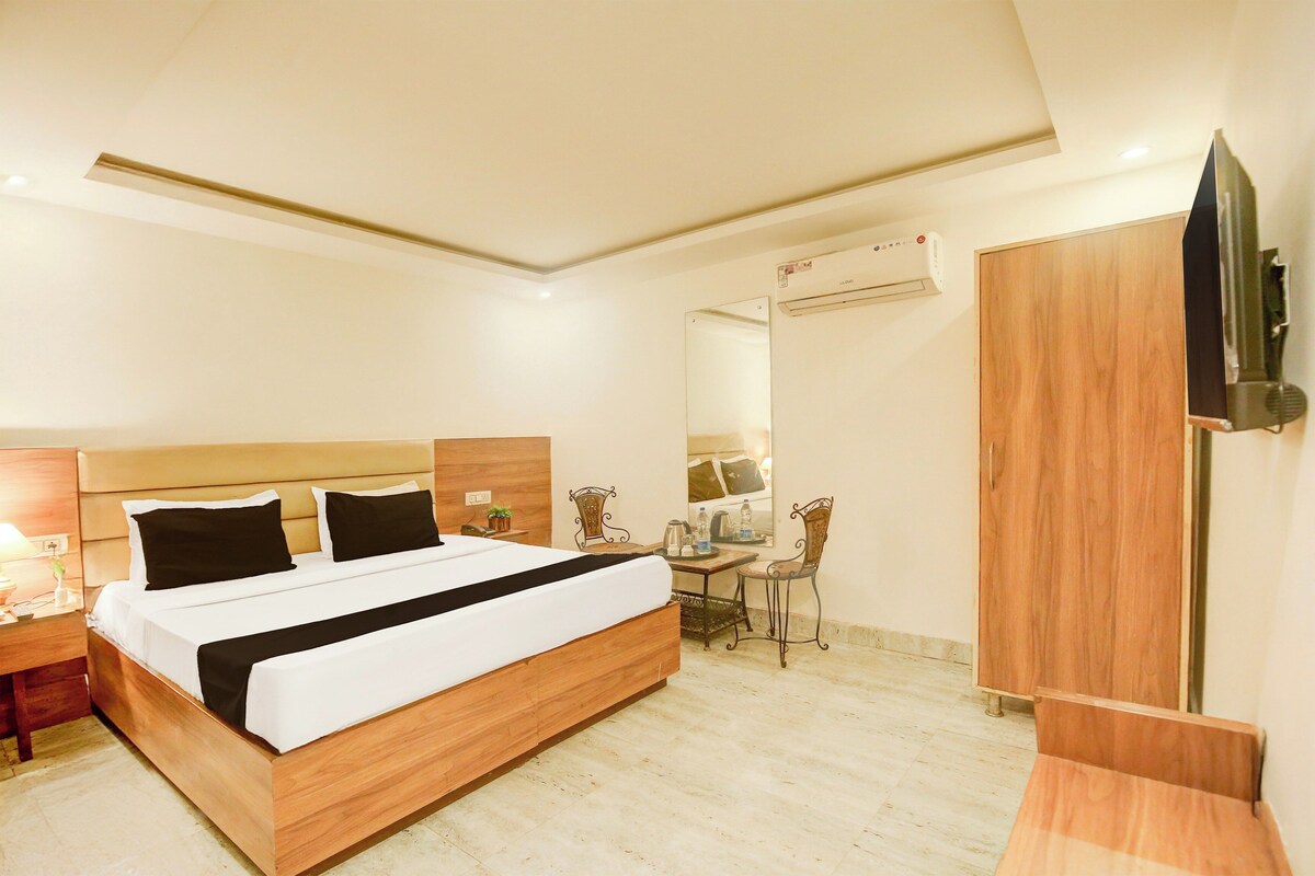 Una habitación de hotel con cama, mesita de noche, silla, escritorio y armario.