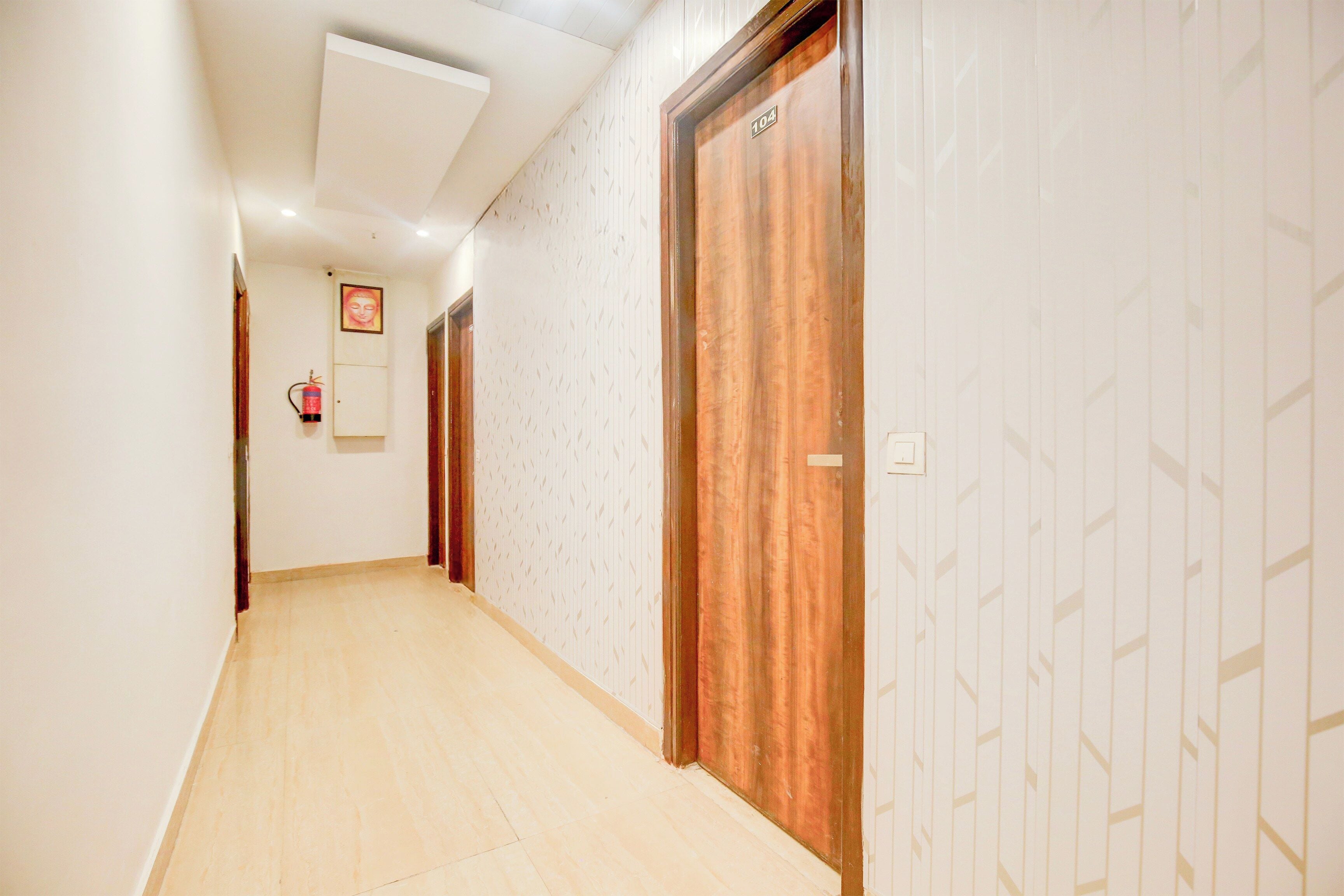 Un pasillo con puertas de madera, papel tapiz estampado y un extintor en la pared.