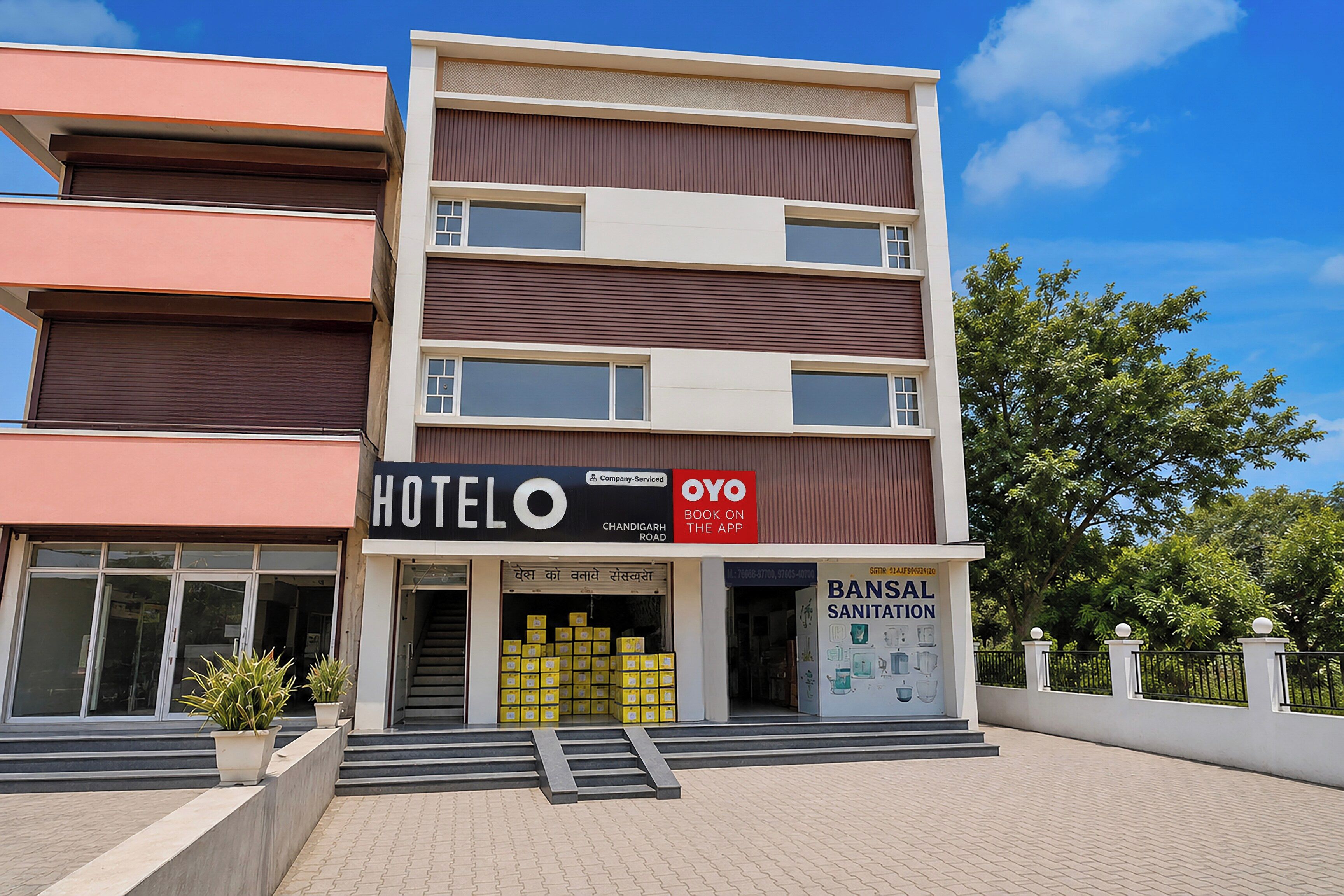 A multi-story hotel with a sign for 'HOTEL OYO' and 'BANSAL SANITATION' services.