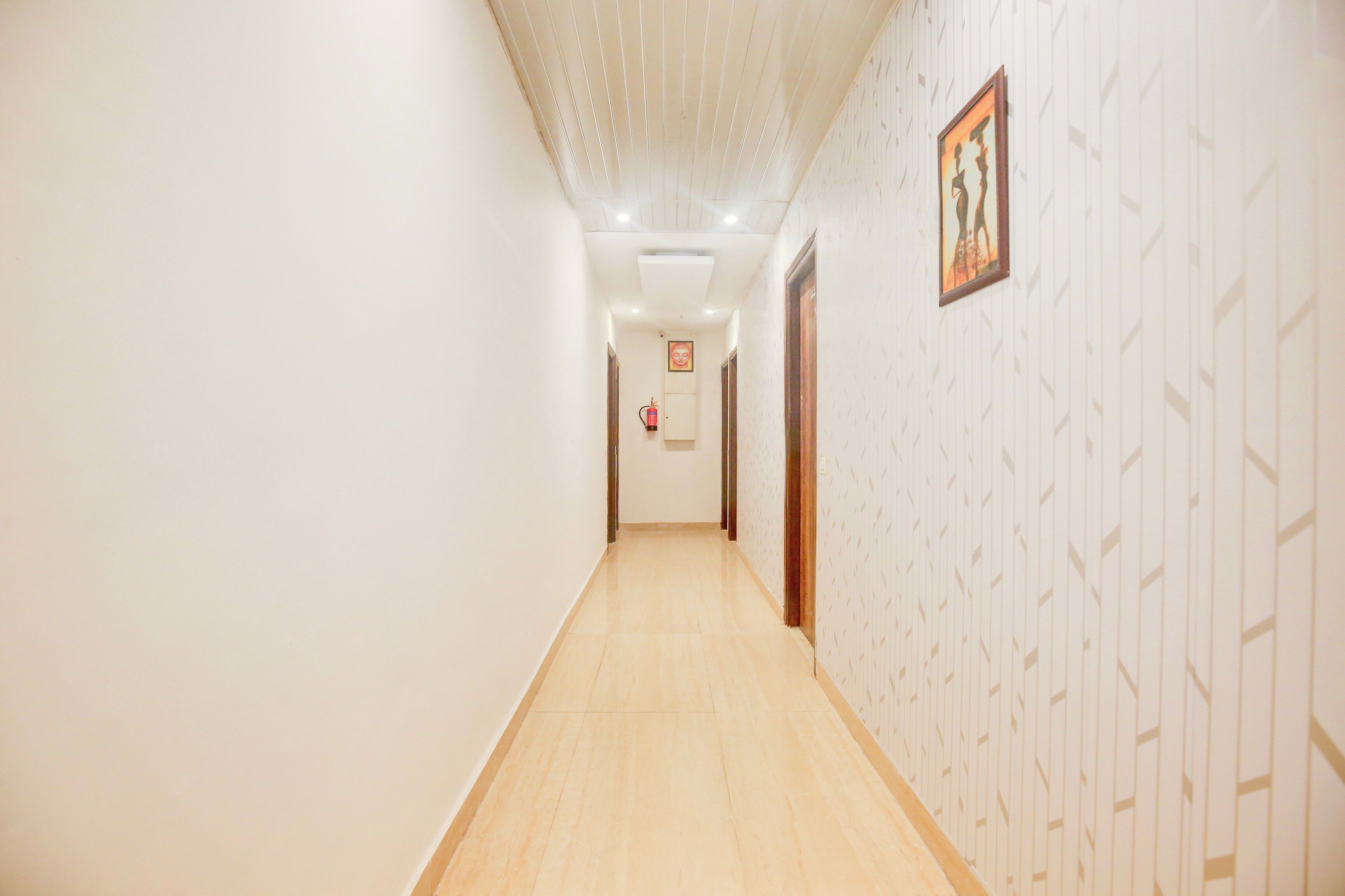 A hallway with patterned wallpaper, a fire extinguisher, and a framed picture on the wall.