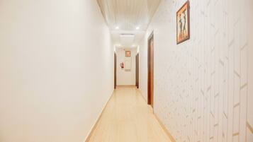 A hallway with patterned wallpaper, a fire extinguisher, and a framed picture on the wall.