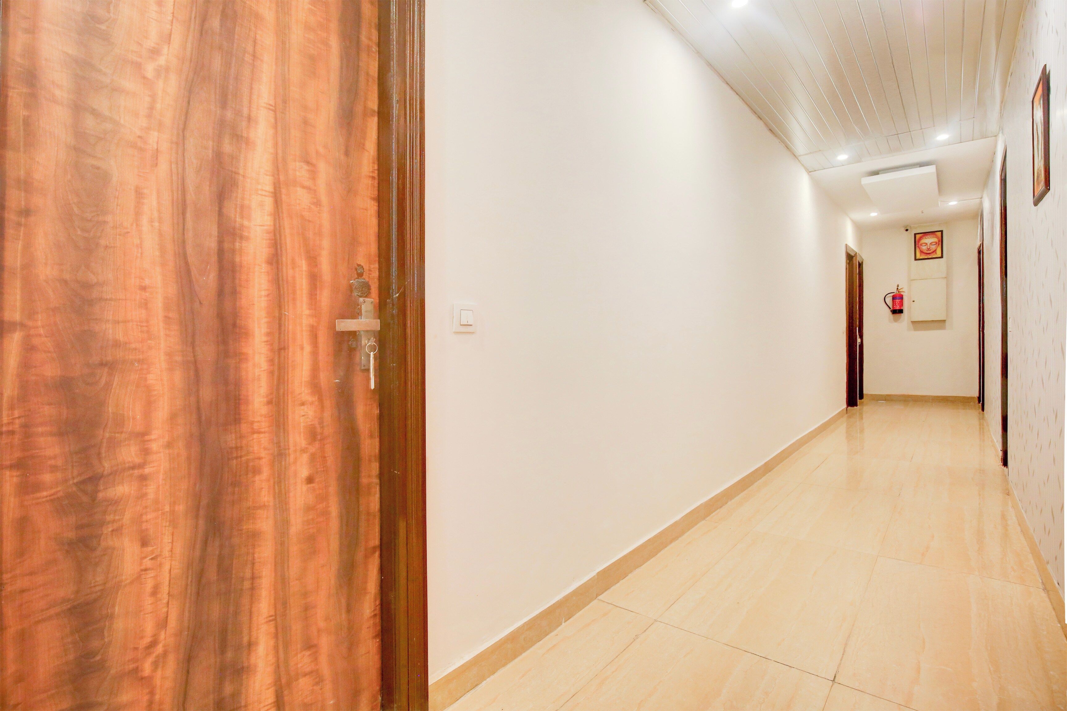 A hallway with a wooden door, white walls, and a tiled floor.