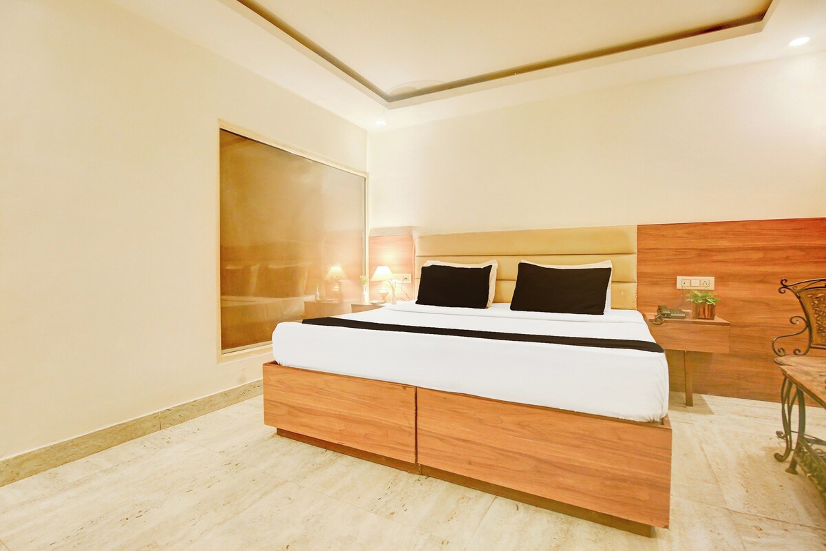 Un dormitorio moderno con una cama grande, cabecera de madera, mesitas de noche y una mesita con lámpara.