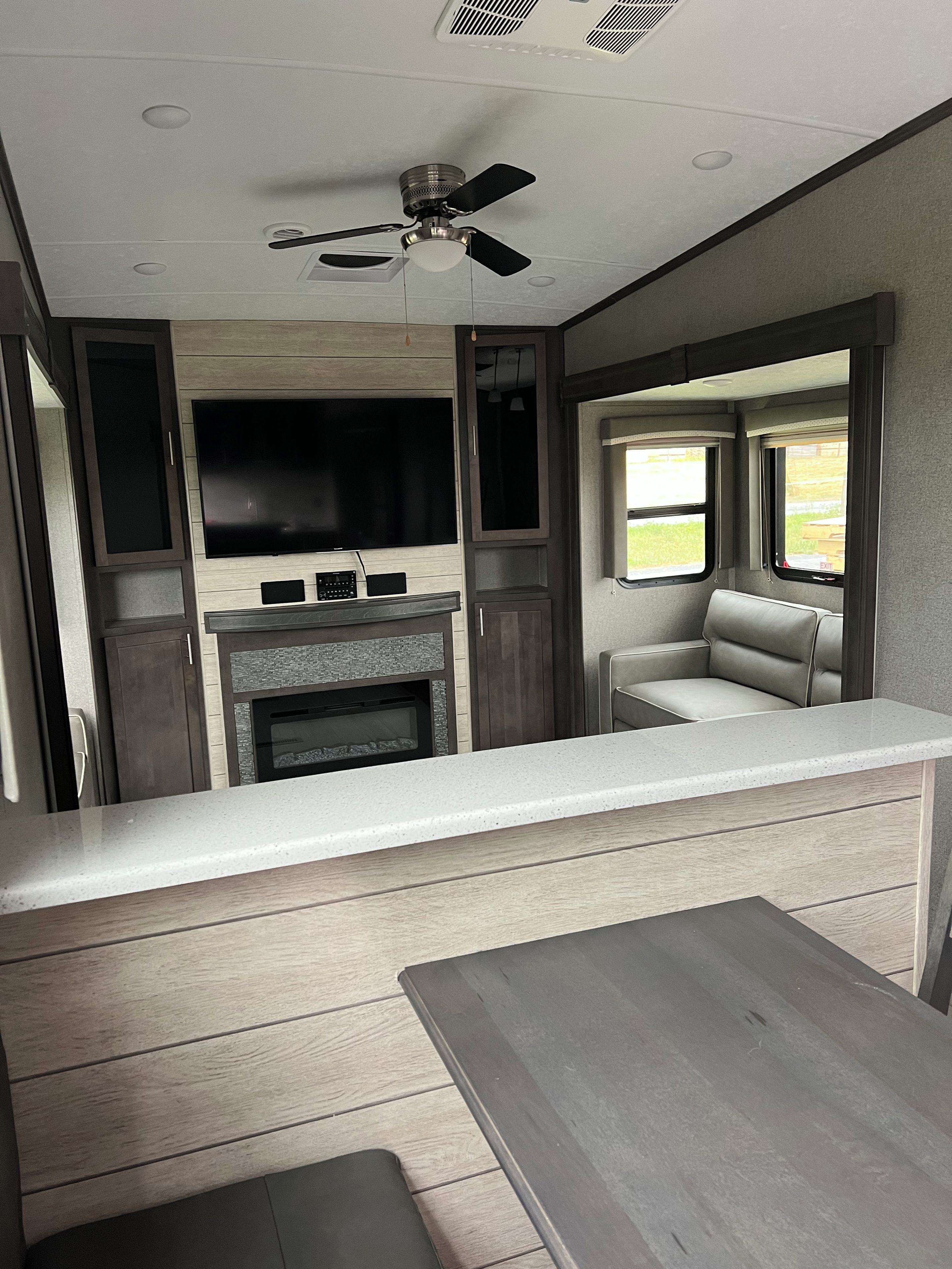 Een compacte keuken met een flatscreen televisie, een inbouwoven en een zithoek met een tafel en stoelen.
