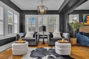 Un salon moderne avec un canapé gris, une table basse ronde et un tapis en peau de vache.