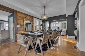 Une salle à manger spacieuse avec une longue table, des chaises en bois et un lustre.