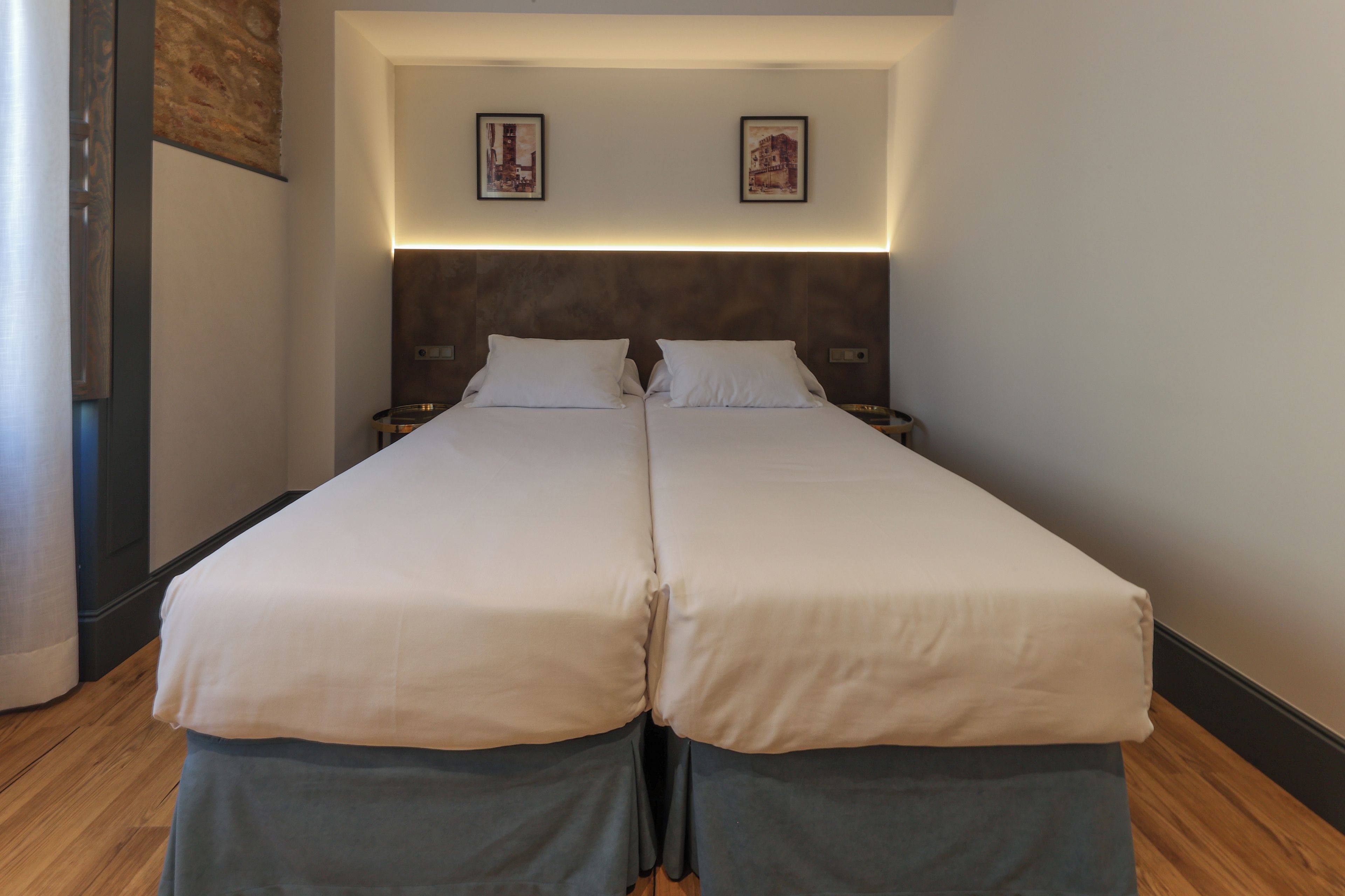 A double bed with two nightstands, a headboard with integrated lighting, and two framed pictures on the wall.