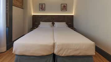 A double bed with two nightstands, a headboard with integrated lighting, and two framed pictures on the wall.