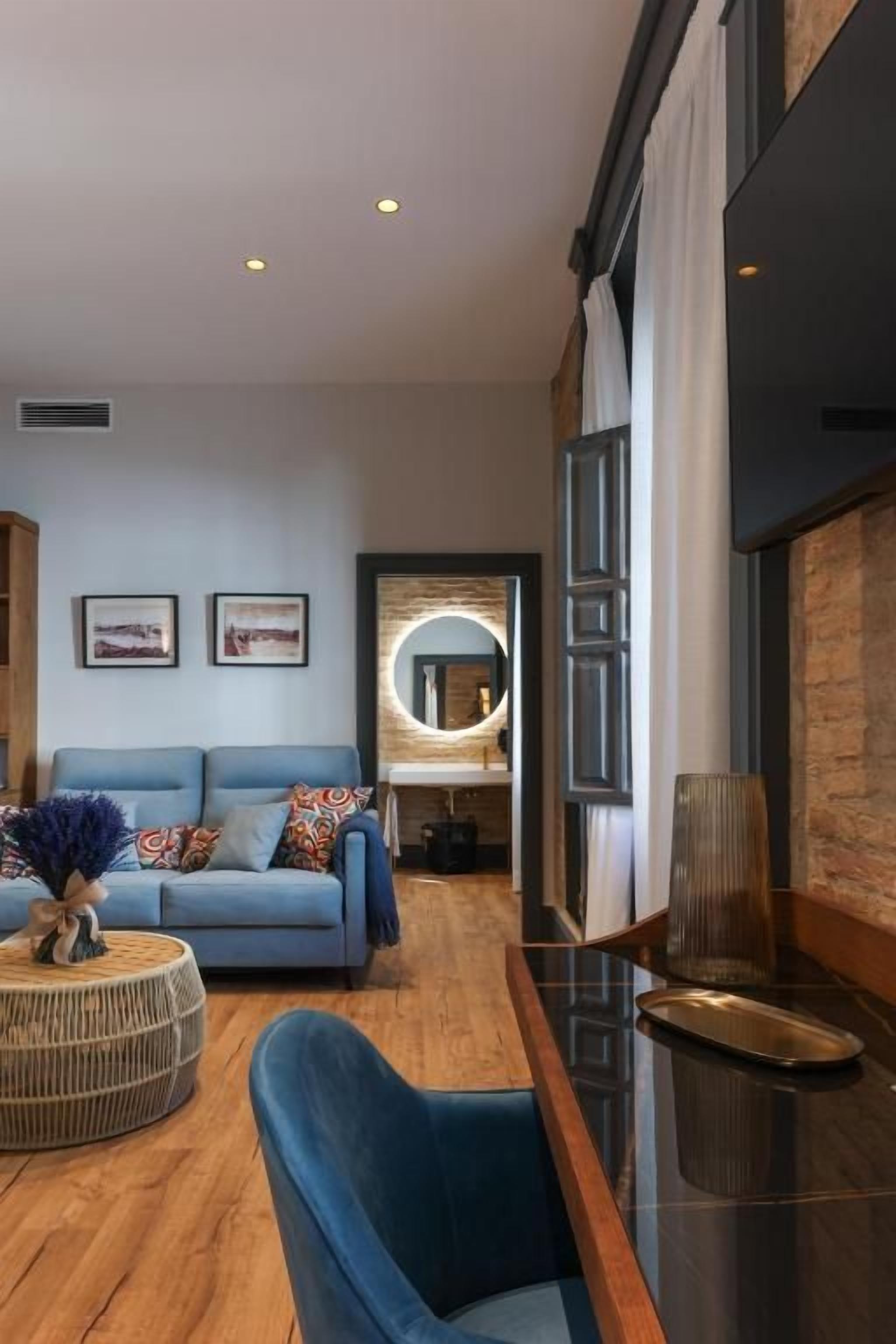 Un interior moderno con un sofá azul, una mesa redonda de centro y piso de madera.