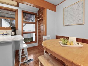 Una cocina con una mesa de madera, taburetes blancos de bar y una ventana con vistas.