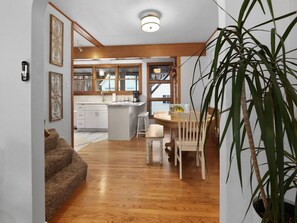 Una cocina compacta con comedor, piso de madera y una planta grande.