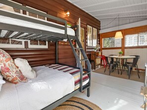 A bunk bed with a ladder, a small table with chairs, and a window with blinds. - Blackberry Cabin | Log Cabin w/ Hot Tub & Beach (Michiana)