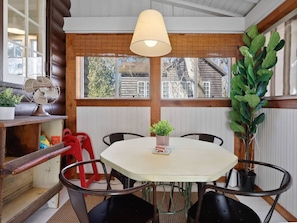 A dining area with a table, chairs, a hanging lamp, and potted plants. - Blackberry Cabin | Log Cabin w/ Hot Tub & Beach (Michiana)