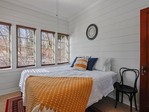A bedroom with a bed, a chair, and a door.