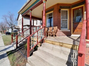 A residential property with a front porch, a set of stairs, and a door. - Blarney Downtown Penthouse & Private Yard (Michigan City)