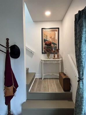 A staircase with a white console table, a framed picture, and a small brown box. - Dragonfly in the Pines | Remodeled Forest Getaway (Michigan City)