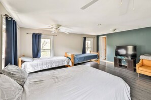 Ein Schlafzimmer mit zwei Betten, einem Deckenventilator, einem Fernseher und einem Sofa.