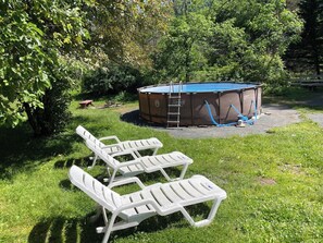Ein Garten mit Trampolin, Pool und Liegestühlen.