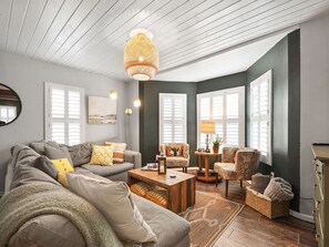 A modern living room with a sofa, armchairs, a coffee table, and a lamp. - Dune Blast Cottage | Hot Tub, Fire Pit & Beach (Michigan City)
