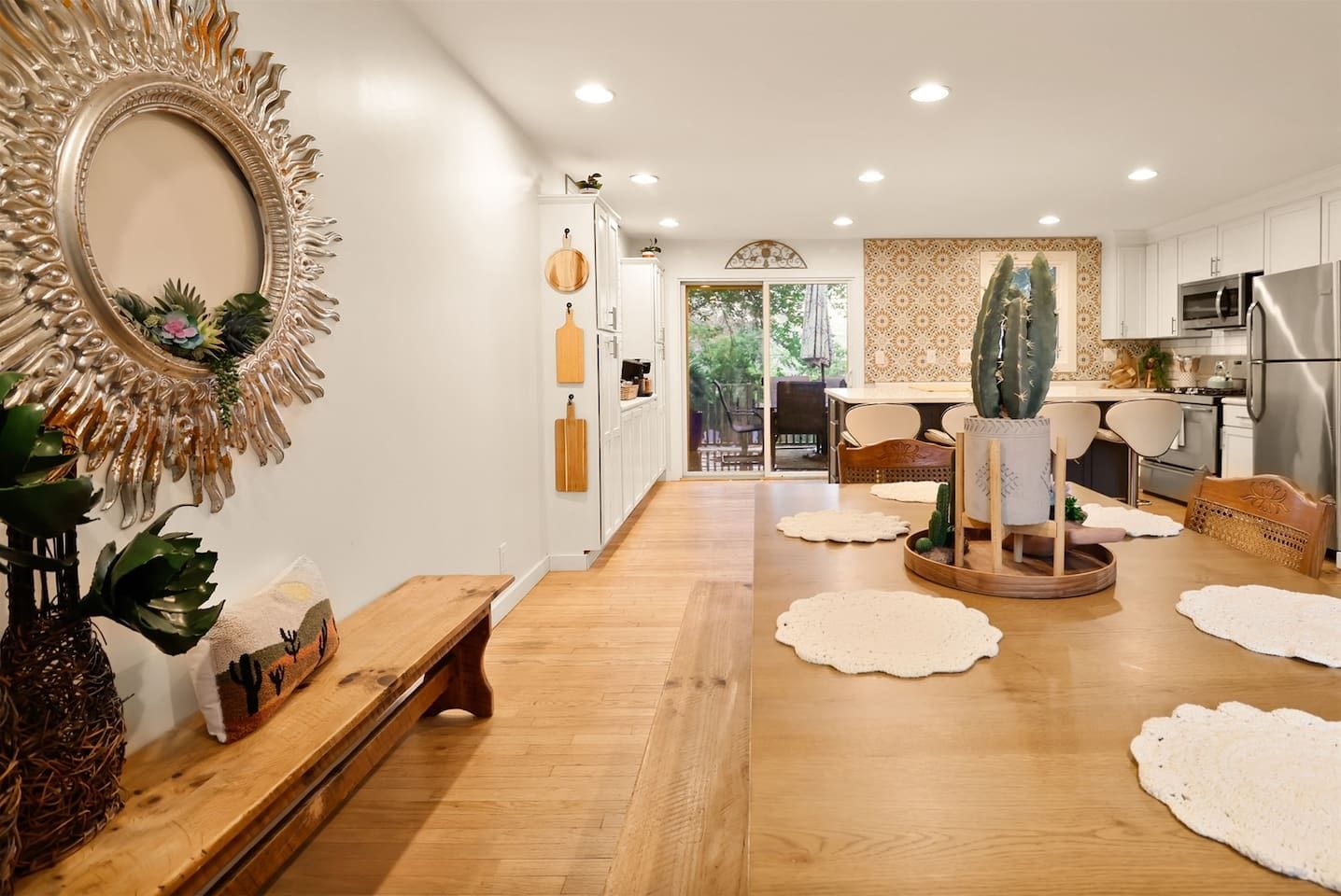 Una cocina moderna con armarios blancos, electrodomésticos de acero inoxidable y una mesa de comedor de madera.