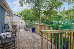 A wooden deck with outdoor furniture, a blue potted plant, and a view of a residential area. - La Casita del Sol | Family Retreat Near the Lake (Michigan City)