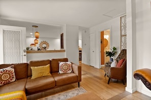 A living room with a brown leather sofa, a patterned rug, and a wooden floor. - La Casita del Sol | Family Retreat Near the Lake (Michigan City)