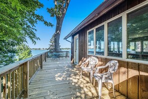 Een houten terras met een tafel en stoelen, uitkijkend op een waterpartij.