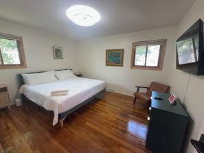 A bedroom with a bed, a chair, a desk, and a television. - The Lake Hills Hideaway Newly Remodeled Beach Retr (Michigan City)