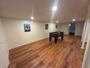 A spacious room with wooden flooring, a foosball table, and artwork on the walls. - The Lake Hills Hideaway Newly Remodeled Beach Retr (Michigan City)