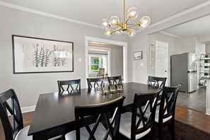 A dining room with a dark wooden table and chairs, a chandelier, and a framed artwork on the wall. - The Veranda — A Timeless Michigan City Classic (Michigan City)